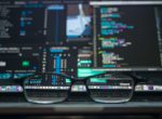PC-Bildschirm mit Programmiercode und Brille